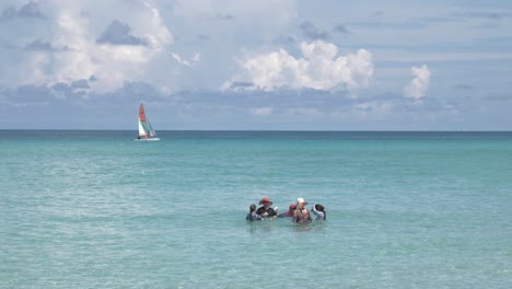 Familie-Badet-Im-Meer,-Im-Hintergrund-Segelt-Ein-Katamaran