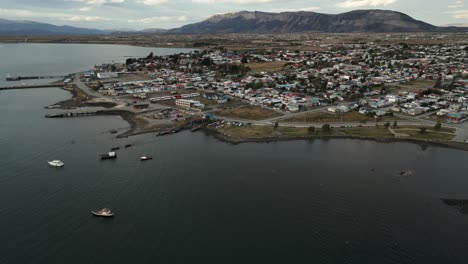 Vista-Aérea-Del-Paisaje-Urbano-De-Puerto-Natales-Chile-Sobre-La-Costa-De-Agua-Patagónica,-Casas,-Calles,-Botes-En-La-Ciudad-Patagónica,-Parque-Nacional-Torres-Del-Paine