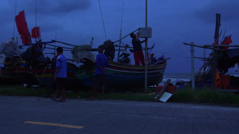 Personas-Que-Cuidan-Botes-De-Madera-Tradicionales-En-Un-Clima-Ventoso-Peligroso-En-La-Noche,-Songkhla-En-Tailandia