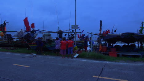 Gente-Protegiendo-Un-Colorido-Bote-De-Madera-Con-Fuertes-Vientos-En-Songkhla,-Tailandia,-Luz-Azul-Vespertina