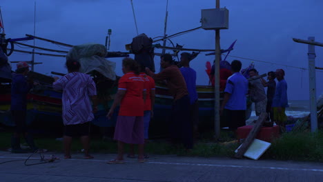 People-protecting-traditional-wooden-boat-on-the-shore-in-heavy-wind-in-Thailand