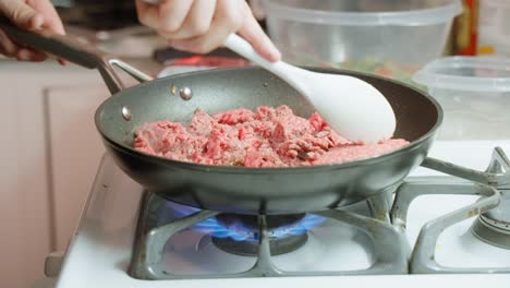 Kaukasische-Männliche-Hand-Zerkleinert-Rohes-Hackfleisch-In-Der-Pfanne-über-Dem-Gasbrenner