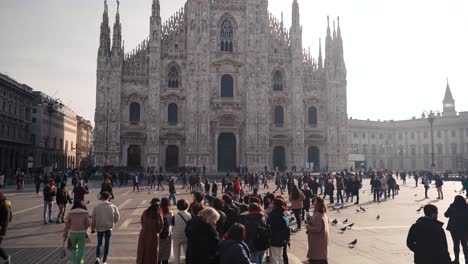 Frontal-view-of-Duomo-Milano-Cathedral-in-Milan-with-people-walking-on-open-square,-camera-movement,-downtown-view-of-Italian-city-with-tourists