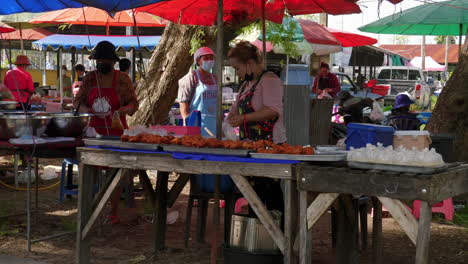 Mujer-Preparando-Comida-Callejera-En-El-Mercado-De-Agricultores-En-Tailandia