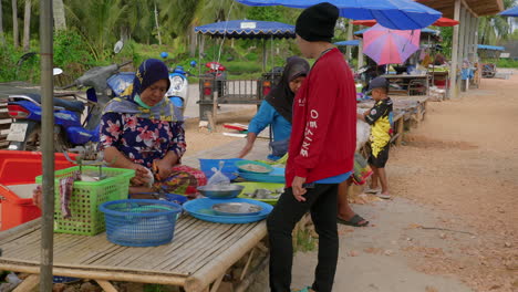 Alte-Frau-Verkauft-Fisch-An-Kunden-Im-Streetfood-Stand-In-Songkhla,-Thailand