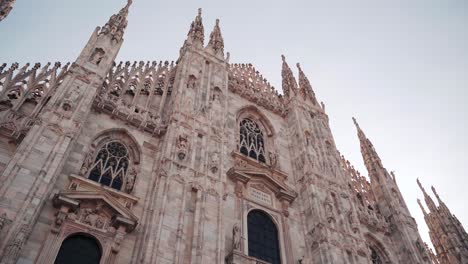 Frontal-view-of-Duomo-Milano-Cathedral-in-Milan-with-people-walking-on-open-square,-camera-movement,-downtown-view-of-Italian-city-with-tourists