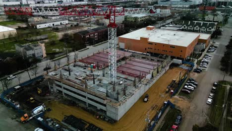 Aerial-view-away-from-a-industrial-construction-site,-in-cloudy-Houston,-USA---pull-back,-tilt,-drone-shot