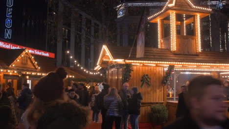 Gente-Caminando-Y-Merodeando-Por-El-Mercado-Navideño-En-Leicester-Square,-Londres,-Reino-Unido