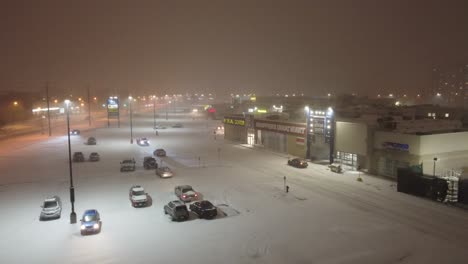 Vista-Aérea-De-Un-Centro-Comercial-Cubierto-De-Nieve-Por-La-Noche-Con-Luces-Coloridas-Y-Actividad-Bulliciosa,-Perfecto-Para-Vacaciones-De-Invierno-Y-Temas-Comerciales