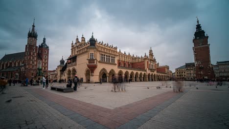 Lapso-De-Tiempo-De-Bucle-Infinito-De-Stare-Miasto,-Rynek-Główny-Casco-Antiguo-De-Cracovia-En-Un-Día-Nublado-De-Invierno-Con-La-Basílica-De-Santa-María-Y-La-Torre-Del-Ayuntamiento-En-El-Fondo