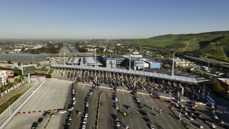 Coches-Haciendo-Cola-En-El-Puerto-De-Entrada-De-San-Ysidro,-En-Tijuana,-México---Ascendente,-Vista-Aérea