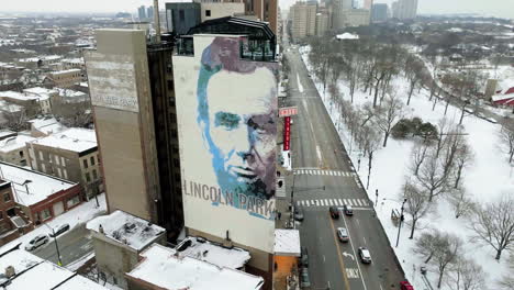 Birds-flying-in-front-of-the-Lincoln-artwork,-winter-in-Chicago,-USA---aerial-view