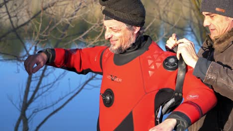 A-diver-in-a-red-wetsuit-is-helped-to-get-fitted