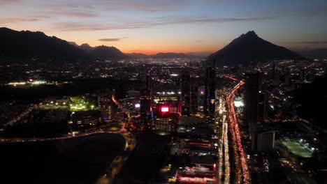 Descripción-Aérea-Del-Paisaje-Urbano-Iluminado-De-San-Pedro-Garza-Garcia,-Monterrey,-Noche-Colorida-En-México