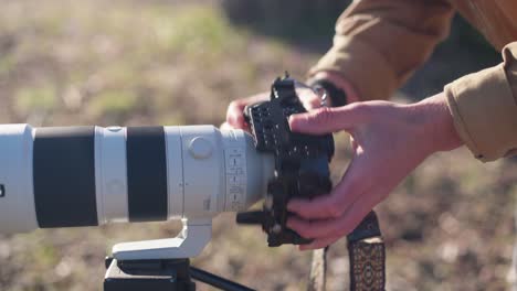 Man-mounting-a-sony-camera-to-a-telephoto-lens-outside-in-the-sun