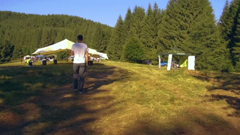 Toma-De-Seguimiento-Siguiendo-A-Un-Joven-Adulto-Milenario-Caminando-Por-Un-Sendero-En-Un-Festival-Rumano-En-Las-Montañas