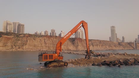 LKW-Bringt-Große-Steine-Zu-Hitachi-Construction-Mit-Großer-Reichweite,-Um-Einen-Steinpier-Zu-Bauen