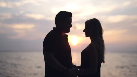 Pareja-Feliz-Tomándose-De-La-Mano-Junto-Al-Lago-Durante-Una-Hermosa-Puesta-De-Sol