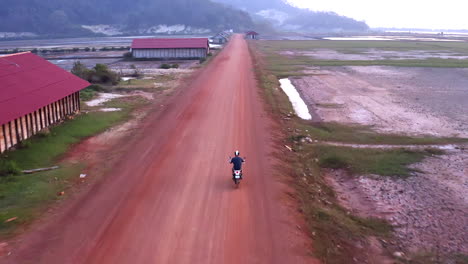 El-Dron-Sigue-A-La-Moto-En-El-Camino-De-Tierra-Camboyano-Hasta-Que-Las-Montañas-Se-Elevan-En-El-Horizonte