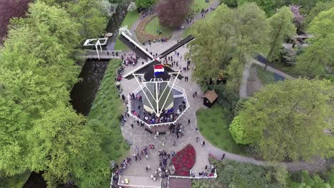 Una-Foto-De-Un-Dron-De-Un-Molino-De-Viento-Holandés-Con-Gente-A-Su-Alrededor,-Panorámica-Hacia-Atrás-Y-Hacia-Arriba,-En-Los-Países-Bajos