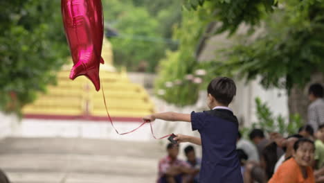 Niño-Birmano-Jugando-Con-Un-Globo-De-Tiburón-Rojo-En-La-Calle-En-Mandalay