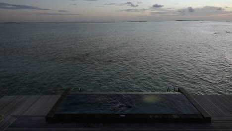 Frau-Schwimmt-In-Der-Dämmerung-In-Einem-Infinity-Pool