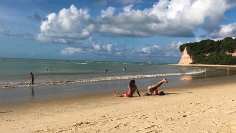 Young-couple-excercising-in-the-beach-with-a-cloudy-sky-as-background