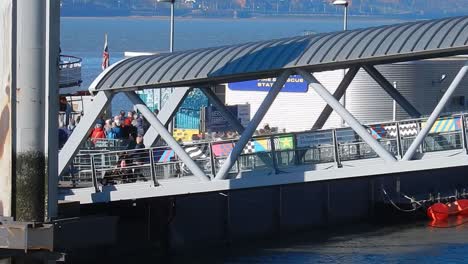 People-walking-down-Liverpool-ferry-port-runway-to-take-tour-around-river-Mersey-tourist-attraction