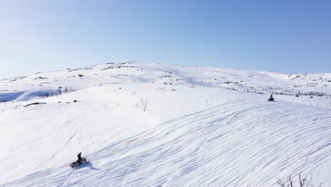 Aerial-view-of-group-of-people-on-snowmobiles-in-snowy-mountain-landscape