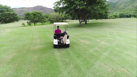 Luftaufnahme:-Seitenansicht-Eines-Mannes,-Der-Einen-Golfwagen-Auf-Dem-Golfplatz-Fährt