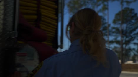 Female-firefighter-preps-gear-on-a-fire-truck-to-be-ready-for-emergency-response-and-firefighting