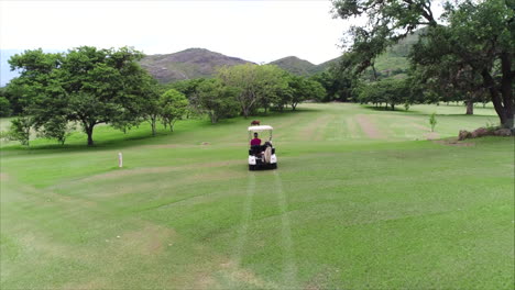 Zeitlupe-Aus-Der-Luft:-Folgender-Mann-Fährt-Golfwagen-Auf-Dem-Golfplatz