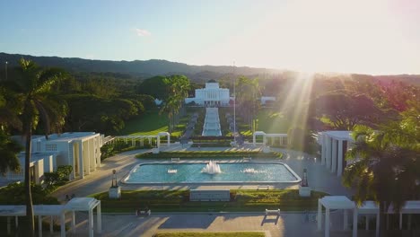 Drohnenaufnahme,-Die-Zwischen-Palmen-über-Das-Wunderschöne-Tempelgelände-In-Richtung-Des-Laie-Hawaii-Mormonentempels-Fliegt