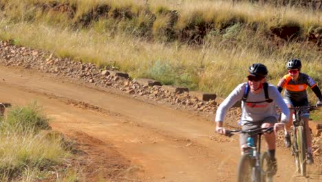 Two-mountain-bikers-racing-past-on-a-gravel-road