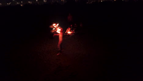 Aerial-Drone-Shot-of-Fire-dancer-dances-on-a-summers-night-on-Brighton-Beach,-England