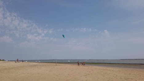 Familia-Con-Niños-De-Vacaciones-Jugando-Con-Una-Cometa-Azul-En-La-Playa-De-Gatseau-En-Oleron