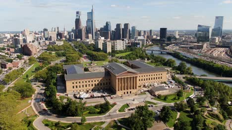 Aerial-drone-descending-shot-of-on-bright-summer-sunny-afternoon,-Fairmount-Park-and-Philadelphia-skyline