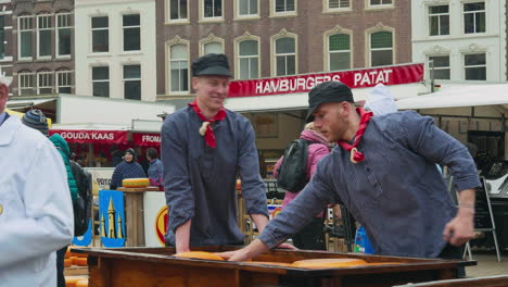 Two-holland-men-in-traditional-clothes-loading-cheese-round-on-cart