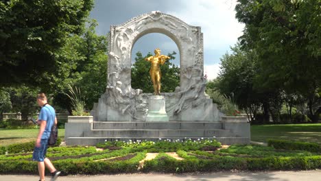 Un-Hombre-Caminando-Frente-Al-Famoso-Monumento-De-Johann-Strauss-En-Stadtpark,-Viena,-Austria-En-Un-Día-Soleado---Tiro-Medio