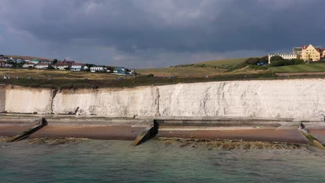 Wide-profile-aerial-tracking-shot-of-the-A259-coast-road-near-Brighton,-UK-with-Roedean-girls-school-passing-through-frame