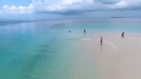 Volando-Por-Encima-De-La-Gente-Y-Los-Barcos-En-Una-Isla-De-Arena-Tropical-Rodeada-De-Aguas-Turquesas-Cristalinas