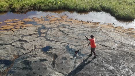 Ein-Reiseleiter-Zeigt-Touristen-Den-Teer-Aus-Der-Mutter-Des-Asphaltsees-In-Trinidad