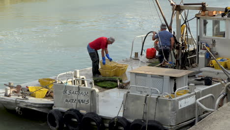 Mittlere-Ansicht,-Austernzüchter-Arbeiten-Auf-Dem-Deck-Ihres-Plattbodenbootes-Nach-Einem-Ausflug-Aufs-Meer,-Hafen-Von-Saint-Trojan-les-Bain,-Insel-Oleron