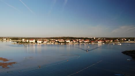 Aerial-panorama-of-a-Nin-town-with-lagoon-and-boat-approaching-in-sunset