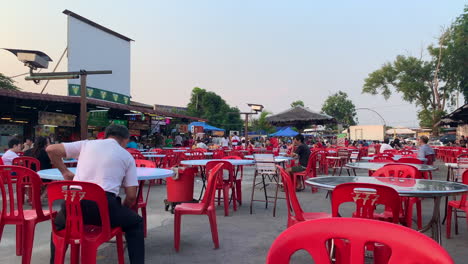 Wide-open-space-but-empty-food-center-with-metal-round-table-and-empty-red-chairs