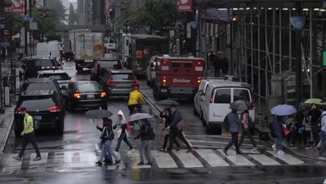 New-Yorkers-crossing-the-street-at-the-intersection-of-east-41st-Street-and-5th-avenue-in-a-massive-rain-at-summer,-filmed-in-180-fps-slow-motion