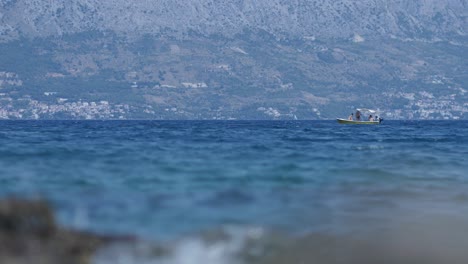 Bote-Pequeño-Estacionario-Distante-En-El-Mar-Abierto-De-Croacia,-Tiro-De-ángulo-Bajo