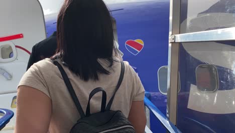 Rear-view-of-passengers-queuing-to-board-an-airplane