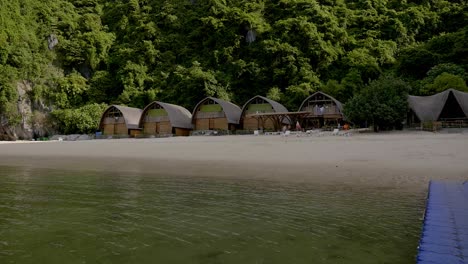 Ha-Long-Bay,-Vietnam---Lovely-view-of-the-Island-with-the-huge-rocky-hills-covered-with-wild-plants-and-the-cottages-in-the-seashore