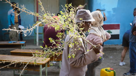 Old-local-Ziway-man-walks-around-a-group-of-people-working-on-restoring-school-in-Ziway,-Ethiopia-during-a-charity-event